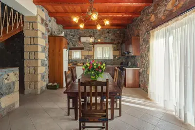 a kitchen with a wooden table with flowers on it at Sea-Sunset Views Villa Lefkothea with Private Pool near Elafonissi in AmigdhalokeFálion