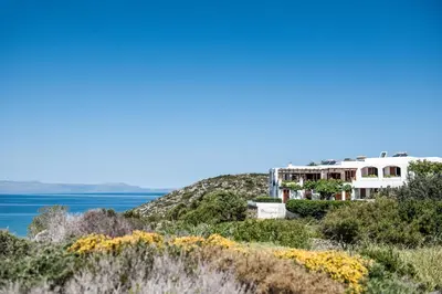 a house on a hill next to the water at Alianthos Villa in Tersanas
