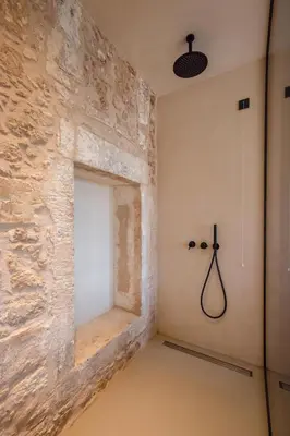 a room with a stone wall and a shower at Monastery Estate Venetian Harbor in Chania Town