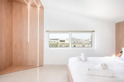 a white bedroom with two beds and a window at Villa Giota in Chania Town