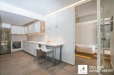 a kitchen with white cabinets and a table and a bathroom at Nikis Dream Comfy Apartments in Chania Town