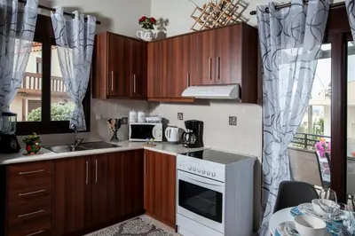 a kitchen with wooden cabinets and a white stove top oven at Kyriaki's Cozy Apartments in Agia Marina Nea Kydonias