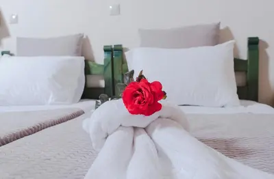 a white bed with a red rose on it at Kyriaki's Cozy Apartments in Agia Marina Nea Kydonias
