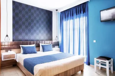 a bedroom with a large bed with blue walls at Kallitsakis Beach in Plataniás
