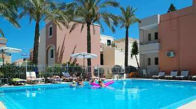 a swimming pool with palm trees and people in it at Kallitsakis Beach in Plataniás