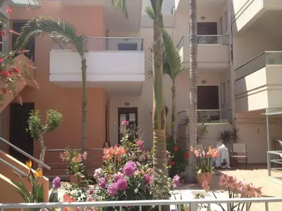 a courtyard with palm trees and flowers in a building at Kallitsakis Beach in Plataniás