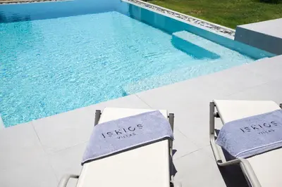 two chairs sitting next to a swimming pool at Iskios Villas in Agia Marina Nea Kydonias
