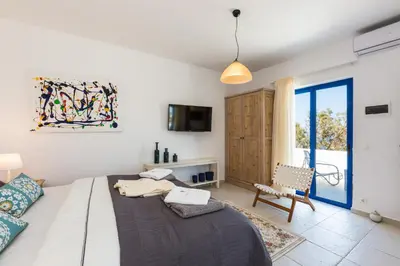 a room with a bed and a chair and a window at Villa Blanca Collection in Kalathas
