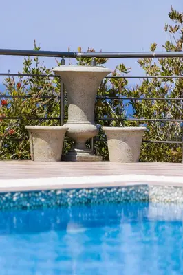a pool with two stone vases next to a fence at Villa Blanca Collection in Kalathas