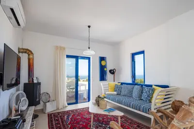 a living room with a blue couch and windows at Villa Blanca Collection in Kalathas