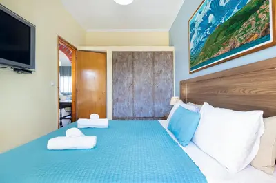 a bedroom with a blue and white bed with a flat screen tv at Irini Apartment II in Kalyves