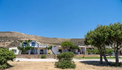 a building with trees in front of a mountain at Adam in Falasarna