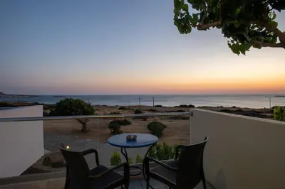 a balcony with chairs and a table and the ocean at Adam in Falasarna