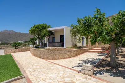 a house with a stone retaining wall and a tree at Adam in Falasarna