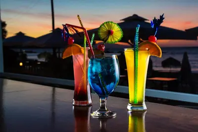 three cocktails sitting on a table with the ocean in the background at Christina Beach Hotel in Chania Town