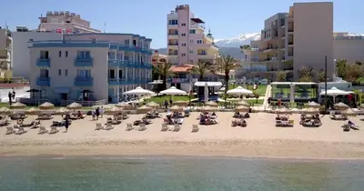 a sandy beach with chairs and umbrellas and buildings at Christina Beach Hotel in Chania Town