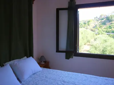 a bedroom with a bed and a large window at Oliaria Apartments in Plataniás