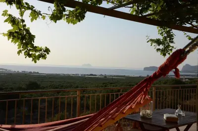 a hammock on a deck with a view of the ocean at Villa Tramonto - Falasarna in Falasarna
