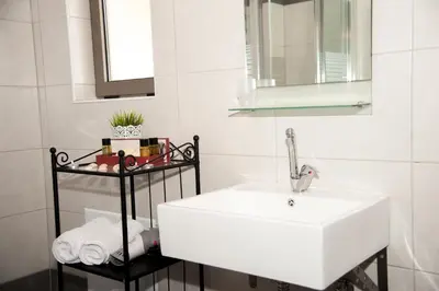 a bathroom with a white sink and a mirror at Efrilias Studios & Apartments in Kissamos