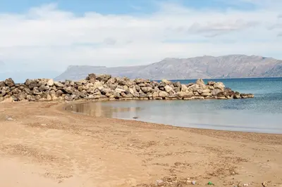 a beach with a pile of rocks in the water at Efrilias Studios & Apartments in Kissamos