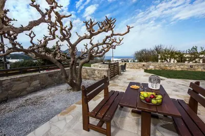 a wooden table and bench on a patio with a tree at Lardas Luxury Country House in Kissamos