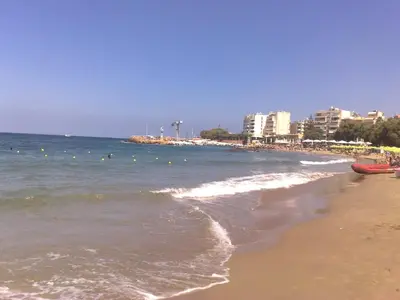 a beach with people in the water and buildings at Stefan's City Hub in Chania Town