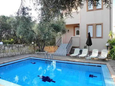 a swimming pool with chairs and a house at Villa-Jasmin in Kato Daratso