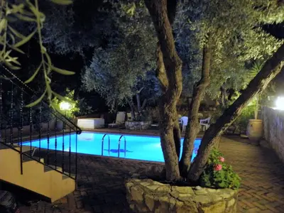 a swimming pool at night with a tree next to it at Villa-Jasmin in Kato Daratso