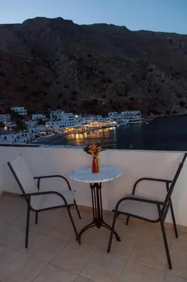 a table and chairs on a balcony with a view of a harbor at Loutro Holidays in Loutro