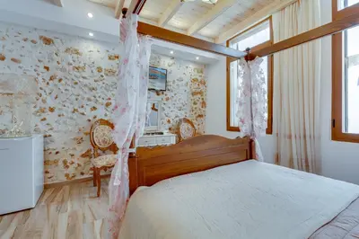a bedroom with a bed in a room with a wall at Hamam Suites Portou in Chania Town