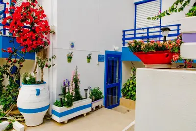 a blue and white building with flowers inront of a door at Blue Sky in Palaiochóra