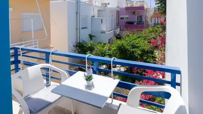 a table and chairs on a balcony with flowers at Blue Sky in Palaiochóra