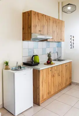 a kitchen with wooden cabinets and a white refrigerator at Kd's - Apartment in Chania Town