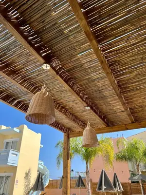 two pendant lights hanging from a wooden pergola at Mediterranea Apartments in Kato Daratso