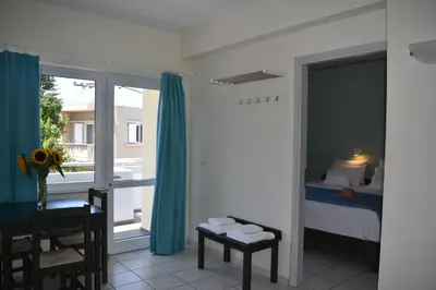 a bedroom with a bed and a table and a window at Mediterranea Apartments in Kato Daratso