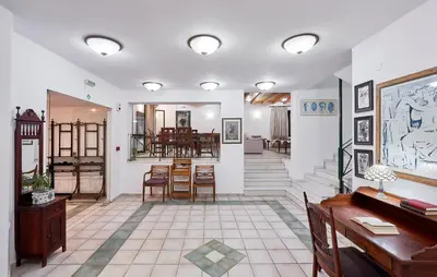 a living room with white walls and tables and chairs at Eva Suites & Apartments in Agia Marina Nea Kydonias