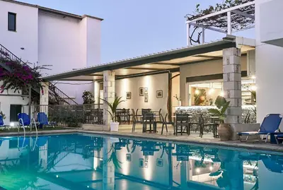 a pool in front of a house with chairs and a patio at Eva Suites & Apartments in Agia Marina Nea Kydonias