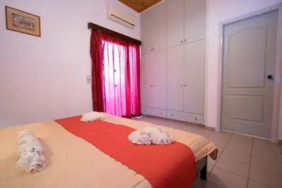 a bedroom with a bed with a red blanket and a window at Mythos- Platanias- Hotel -Apts in Plataniás
