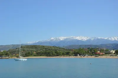 a boat in the water near a beach with mountains at Chryssi myHome in Kato Daratso