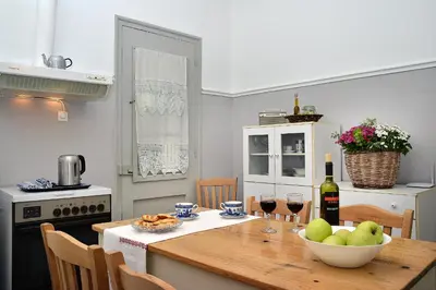 a kitchen with a table with a bowl of fruit and wine glasses at Haralabos Central Apartment in Chania Town