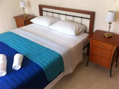 a bedroom with a bed and a nightstand with two lamps at ILIAS VILLA IN CHANIA in Perivólia