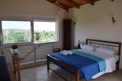 a bedroom with a bed and a large window at ILIAS VILLA IN CHANIA in Perivólia