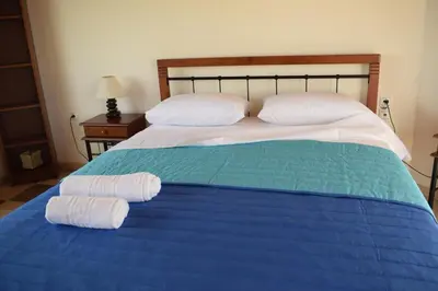 a bed with two towels on it with a blue blanket at ILIAS VILLA IN CHANIA in Perivólia