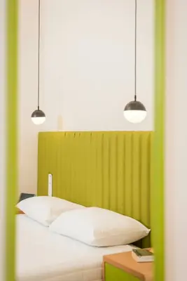 a bed with two pendant lights and a green headboard at TheJoy City Suites in Chania Town