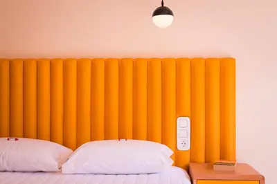 a bed with two pillows in front of a yellow wall at TheJoy City Suites in Chania Town