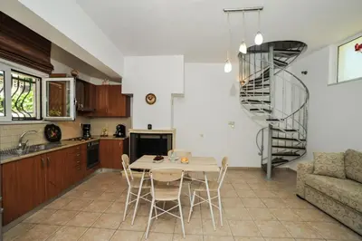 a kitchen and living room with a table and chairs at Romantic Corner Maisonette houses in Stalos