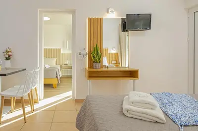 a bedroom with a bed and a table and a mirror at Theos Village Apartments in Kato Daratso