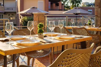 a wooden table and chairs on a patio with wine glasses at Theos Village Apartments in Kato Daratso