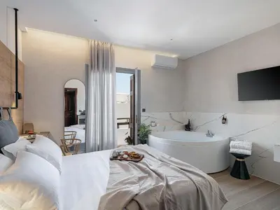 a bedroom with a large bed and a bath tub at Amphitrite Hotel in Chania Town