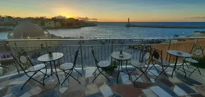 a balcony with tables and chairs and the ocean at Amphitrite Hotel in Chania Town